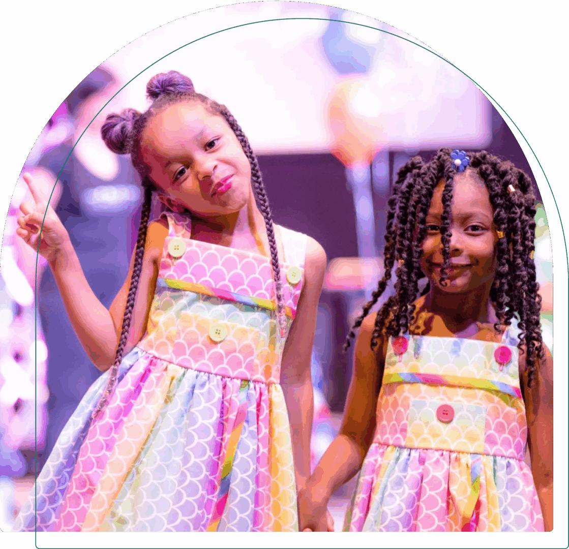 Two girls in colorful dresses smiling.