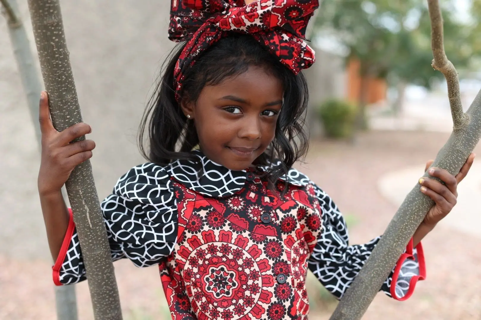 Girl in colorful patterned dress outdoors.