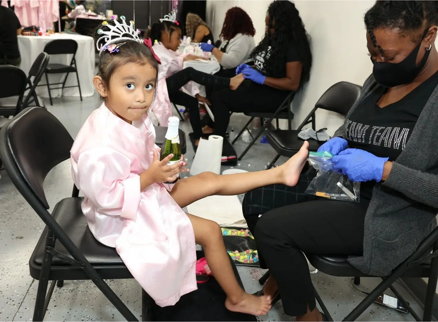 Young girl getting a pedicure, wearing tiara.