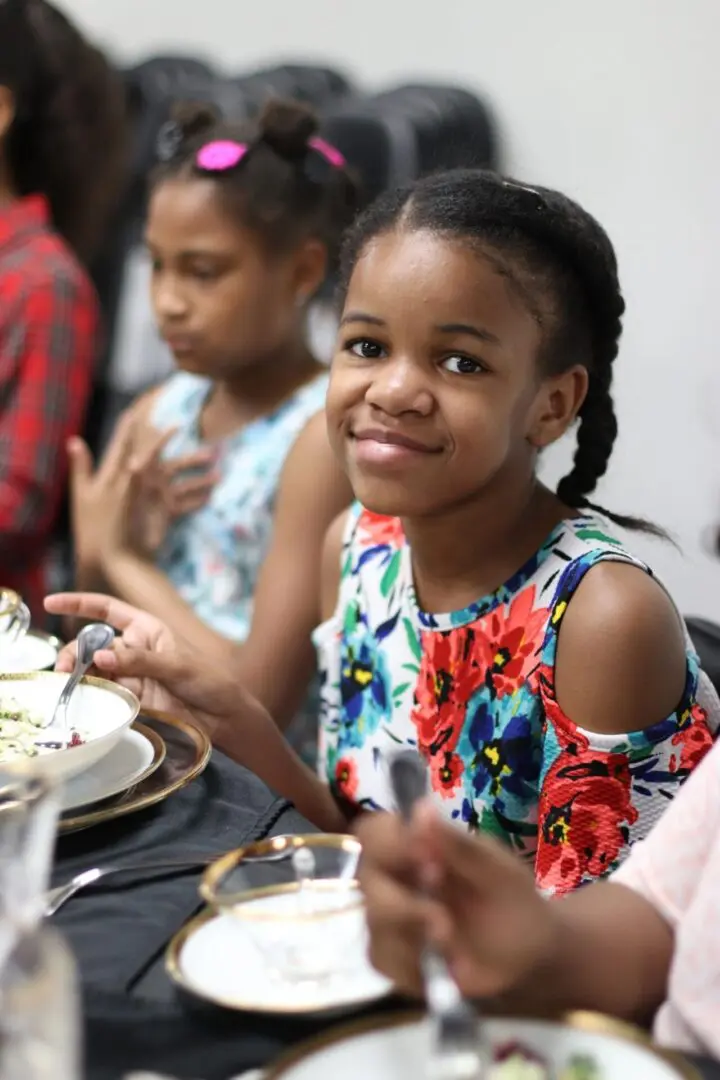 Girl smiling at table with food.
