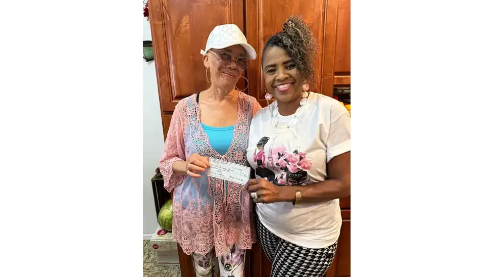 Two women smiling, holding a check.