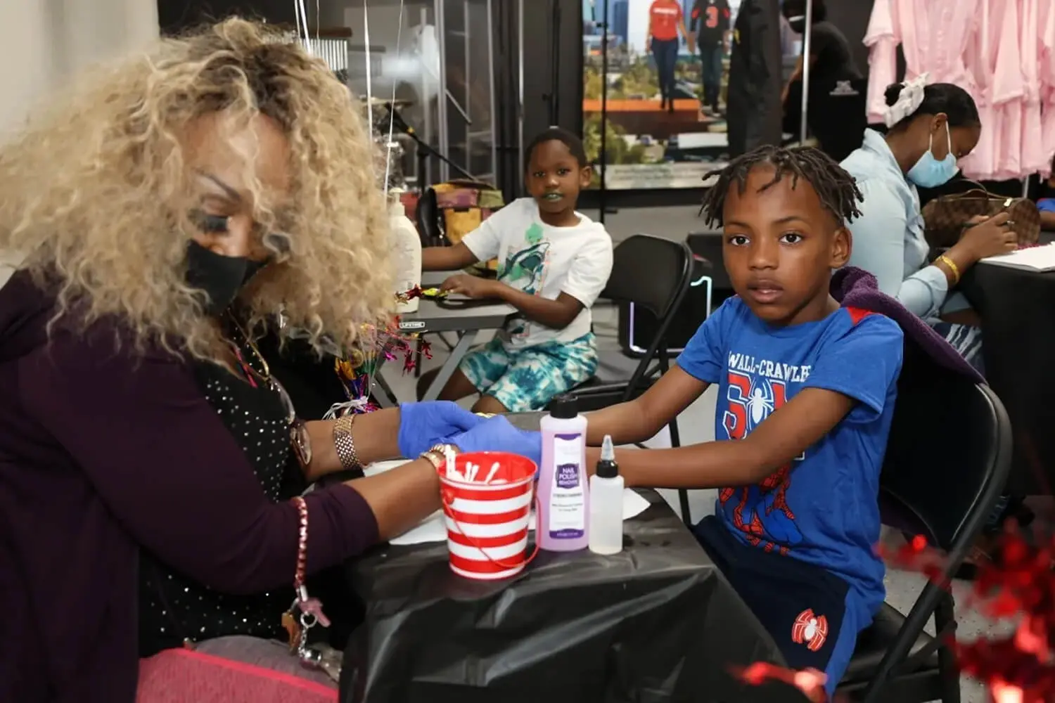 Child receiving manicure at nail salon.