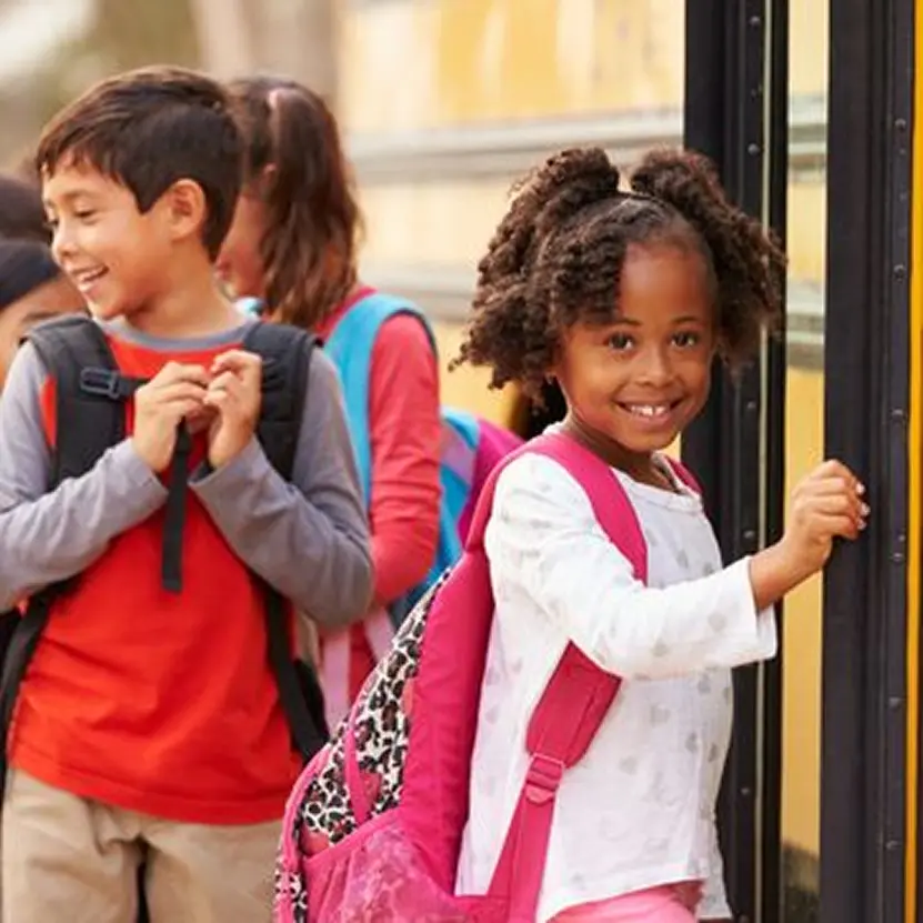 Children boarding a school bus, smiling.
