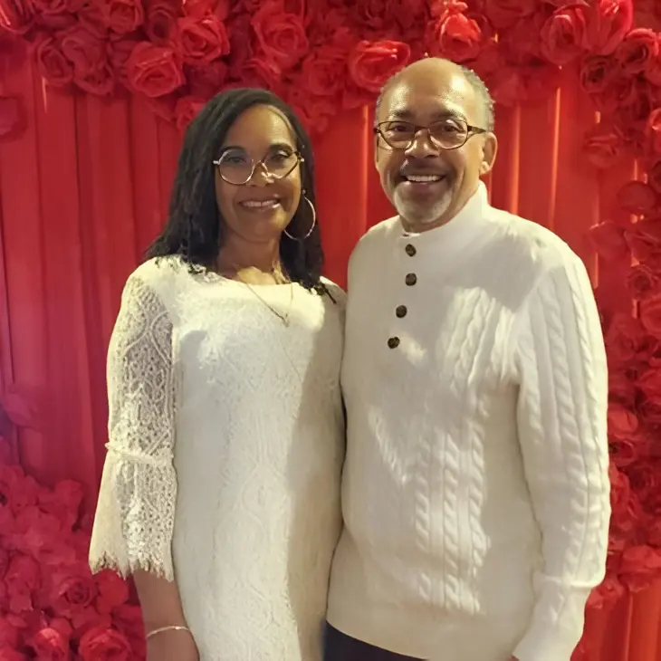 Smiling couple in front of red roses.