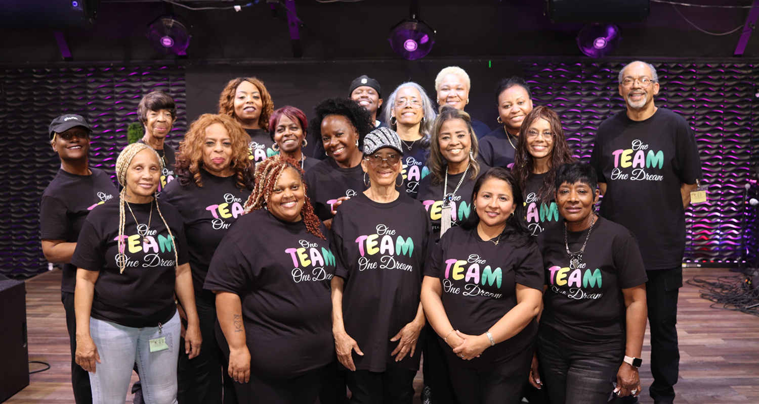 A diverse group of women wearing matching TEAM shirts, smiling at a gathering.